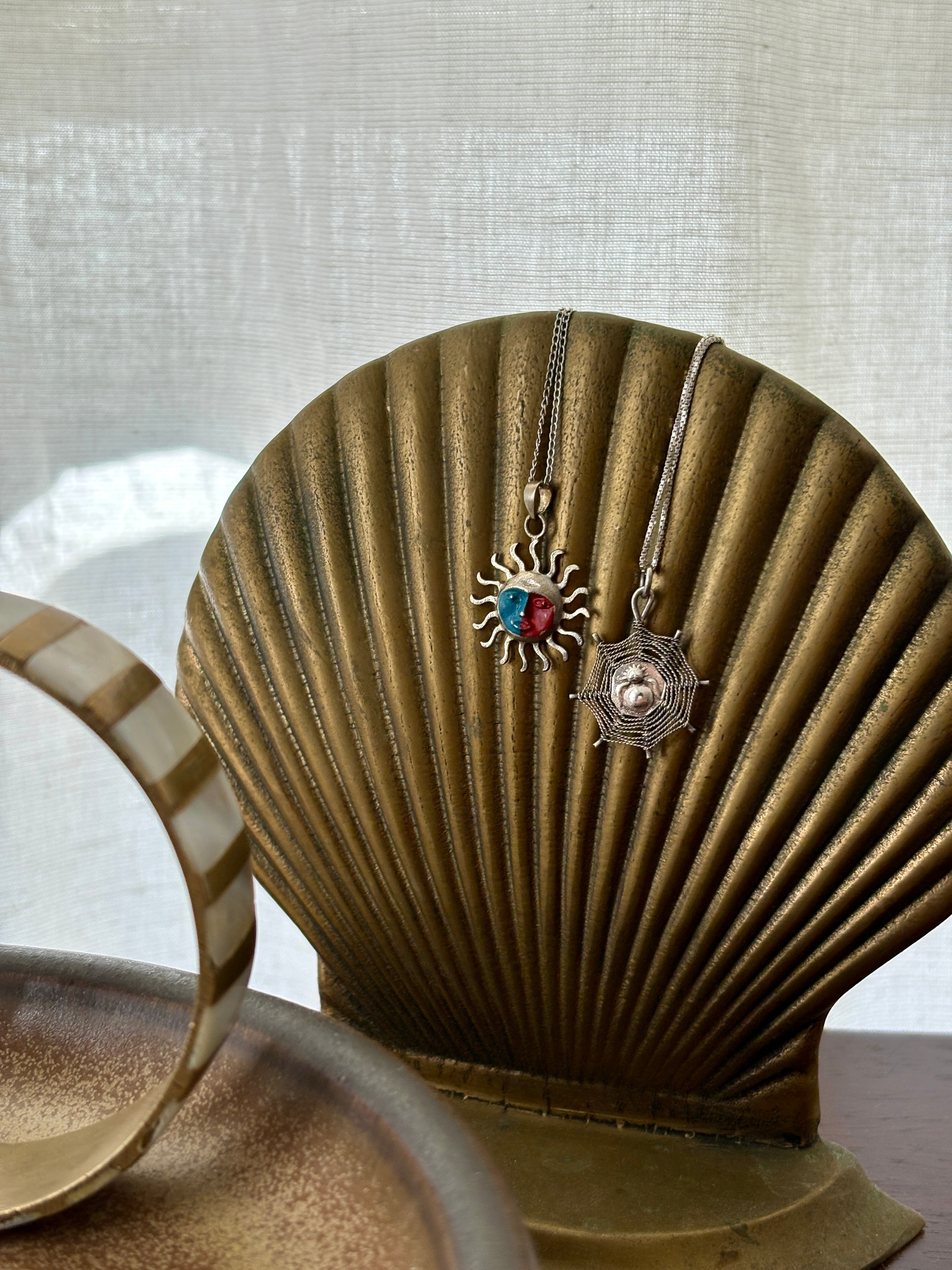 Two necklaces displayed on a decorative shell against a neutral background