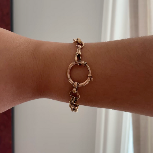 Gold bracelet on a wrist with a neutral background